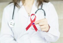 Cancer, mental health and musculoskeletal disorders account for ‘half of employee health referrals’ A doctor wearing holding a red cancer ribbon.