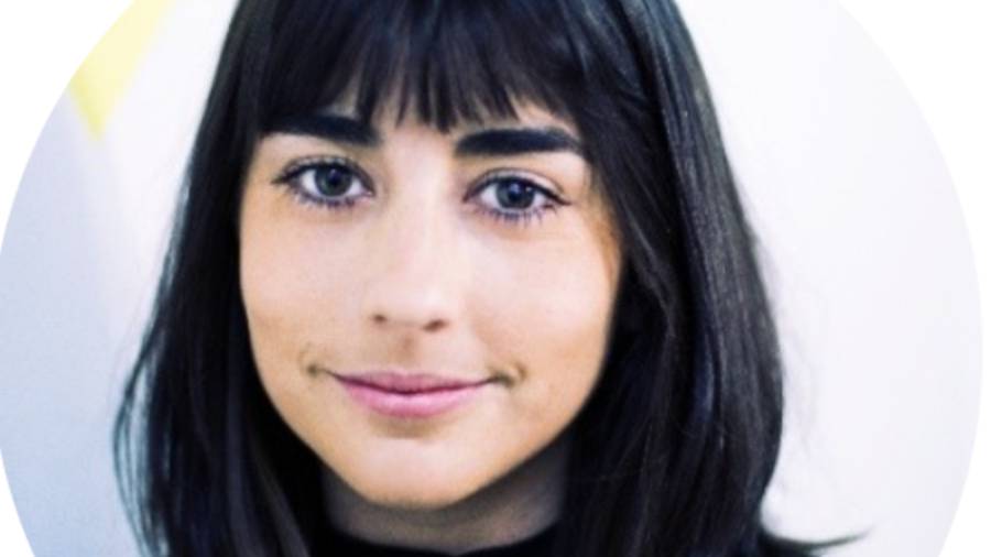 A person with straight dark hair and bangs, wearing a dark top, smiling slightly at the camera against a light background, exudes confidence — a perfect fit for an HR professional.