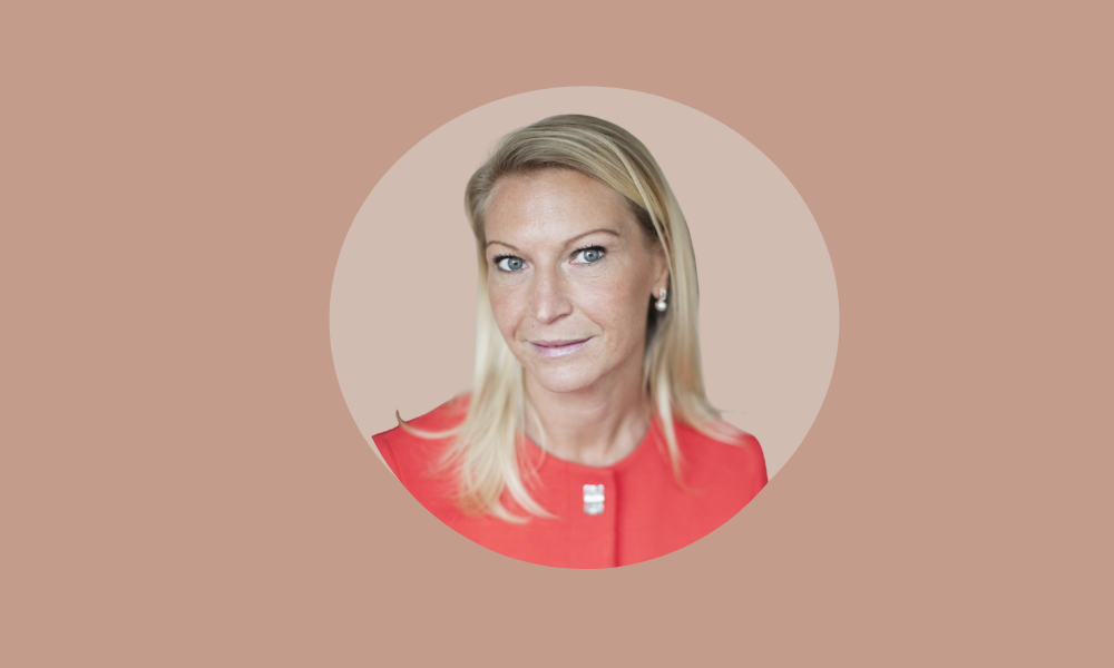 A woman with straight blonde hair wearing a red top is centered in a circular frame against a light brown background, almost as if she’s poised for her annual appraisals.