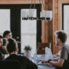 People sit around a table in an office, having a meeting.