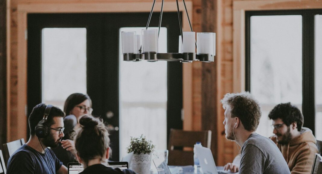 People sit around a table in an office, having a meeting.