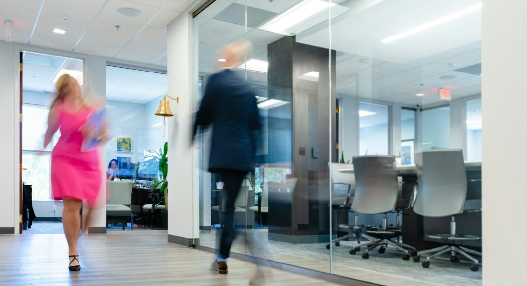 A blurry photo of a man and a woman walking in an office.