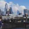 A man in a blue suit and backpack walks along the Thames, with City of London skyscrapers in the background.