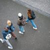 A group of young people walking down a street, viewed from above.