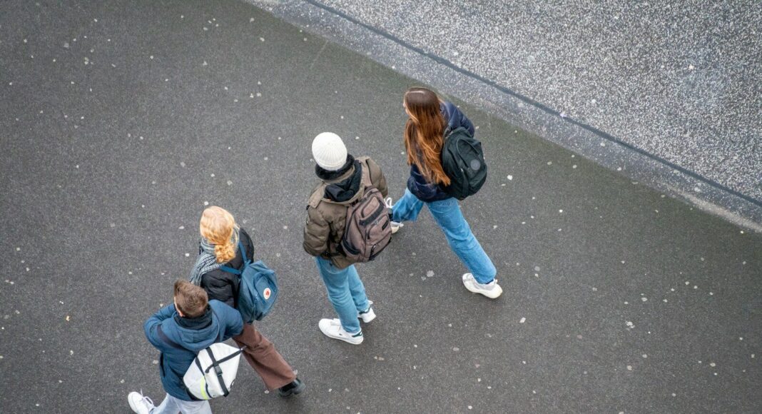 A group of young people walking down a street, viewed from above.