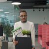 A man carries a box of personal items as he leaves an office after quitting.