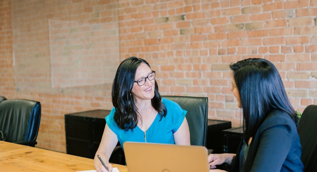 Photo by Amy Hirschi Two women having a performance review meeting at a table.