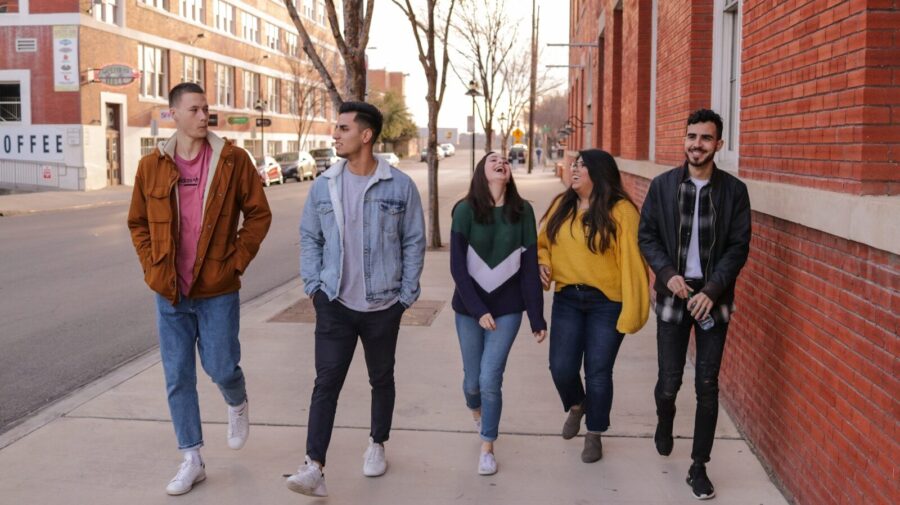 A group of young people walk along a street.