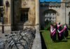 University no longer pays for everyone as employers back apprenticeships Students walk in gowns on campus.