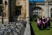 University no longer pays for everyone as employers back apprenticeships Students walk in gowns on campus.