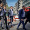 Men in suits walking along a city street.