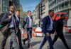 Unemployment falls as private sector pay growth slows to 2.9% Men in suits walking along a city street.