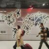 People walk past a glowing world map.