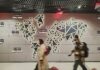 Govt unveils visa support scheme to help scale-ups hire global talent People walk past a glowing world map.