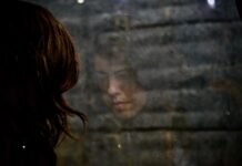 Three million working days lost to mental ill health this year A woman looking out a window, looking sad.