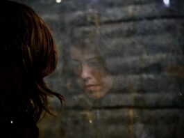 Three million working days lost to mental ill health this year A woman looking out a window, looking sad.