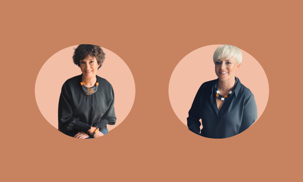 Two individuals are pictured against a peach background, each in circular frames. They are both wearing dark tops and necklaces, one with short curly hair and the other with short blonde hair, celebrating International Women’s Day.