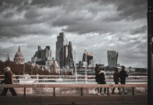 UK set for biggest rise in unemployment among G7 nations, OECD warns People walking across a bridge in London with a grey, stormy sky in the background.