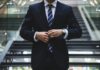 AI is breaking the traditional career ladder A man in a suit stands before the camera.