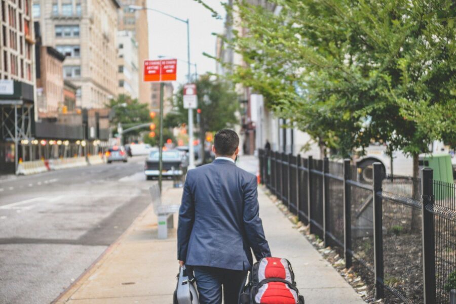 A businessman walking down a street with bags, suggesting he quit his job.