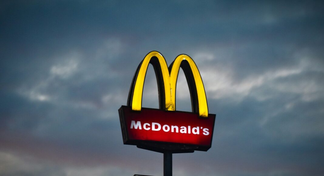 Photo by Jurij Kenda The McDonald's logo and sign with a cloudy sky in the background.