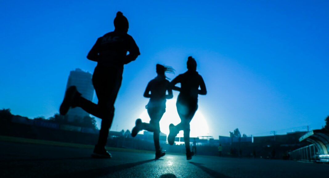 Silhouette of three women running on a road.