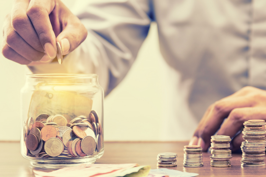 a hand putting money in a jam jar