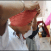 A young man is putting on a turban while displaying an example of cultural sensitivity, showcasing his understanding of diversity and inclusion, which are crucial skills in people management or HR roles within Human Resources.