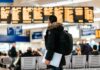 Employers face growing duty of care pressures as business travel costs surge A male passenger stands in front of a departures board at an airport.