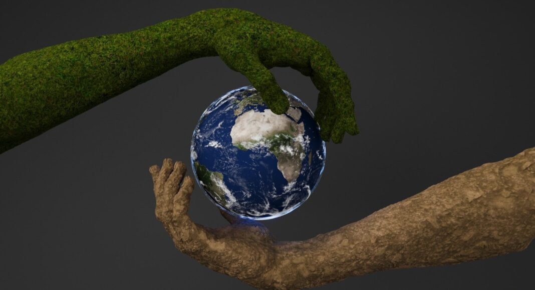 Two hands are holding a small earth globe.