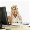 An HR professional is holding her head in front of a computer.