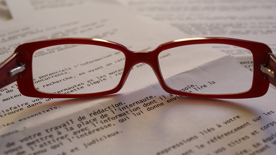 A pair of red-framed eyeglasses is placed on top of several HR documents with printed text.