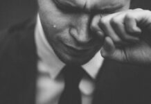 One in three workers ‘dissatisfied in jobs as disengagement and stress rise’ A man in a business sut wiping away tears.