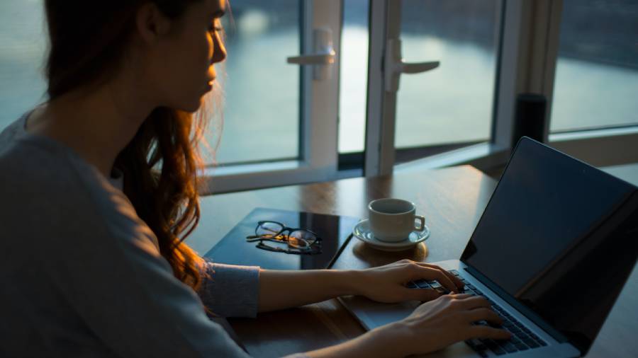 A person sitting at a desk using a laptop with a cup of coffee, glasses, and a notebook nearby, preparing for an upcoming work tribunal.