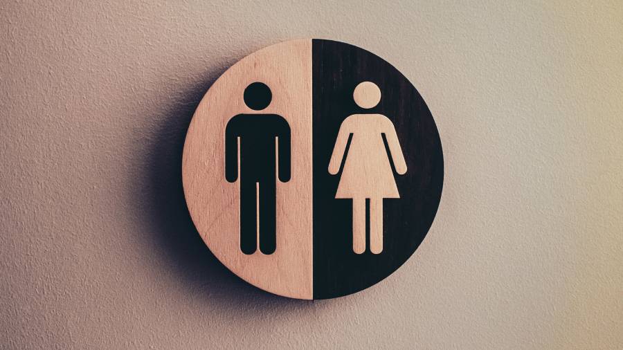 A round sign with a man symbol on the left half and a woman symbol on the right half, indicating a unisex restroom, promotes inclusivity and subtly hints at the need for gender pay gap action.