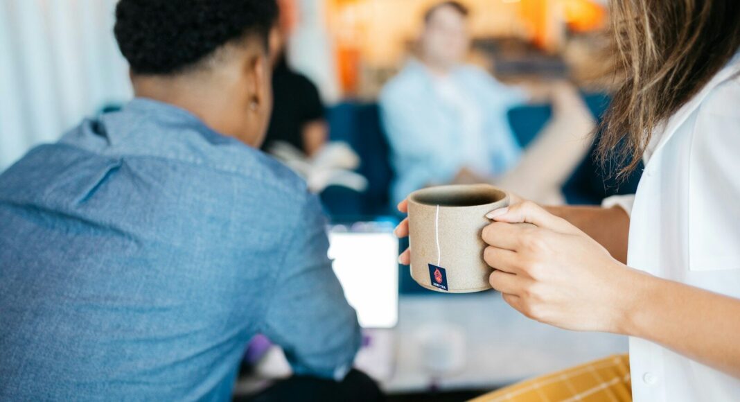 A woman holds a mug of coffee at an office.