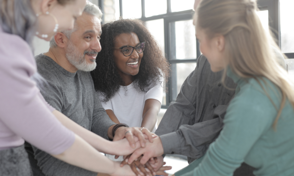 A group of union members placing their hands together in the center in a show of unity and teamwork.