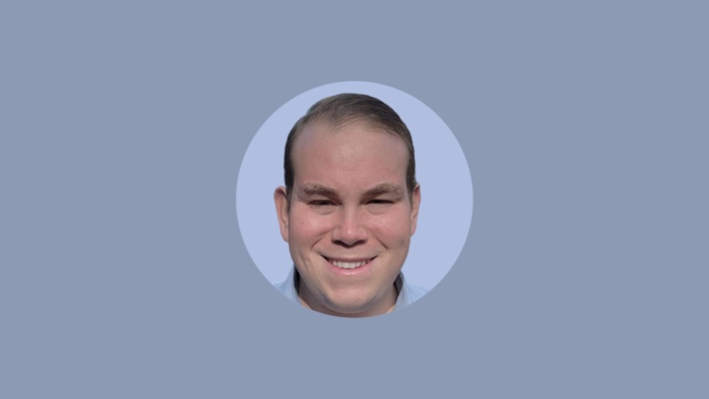 A man with short hair and a light complexion smiles at the camera, shown in a circular frame on a blue background, evoking the fusion of technology and modern aesthetics.