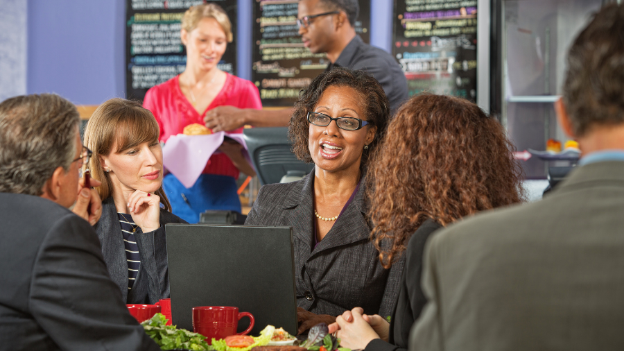 people having lunch in a restaurant with a laptop
