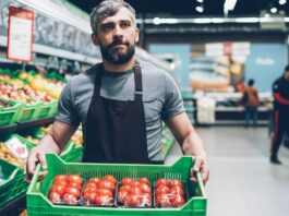 Food workforce crisis deepens as labour shortages threaten supply and service A grocery store worker holds a box of tomatoes.