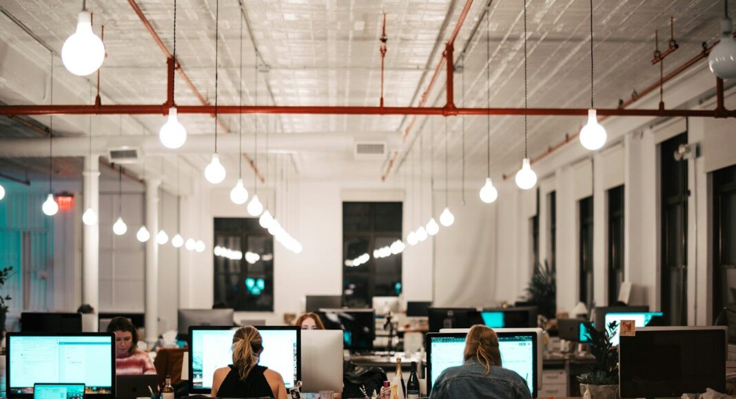 Office staff working at computers in an open-plan setting.