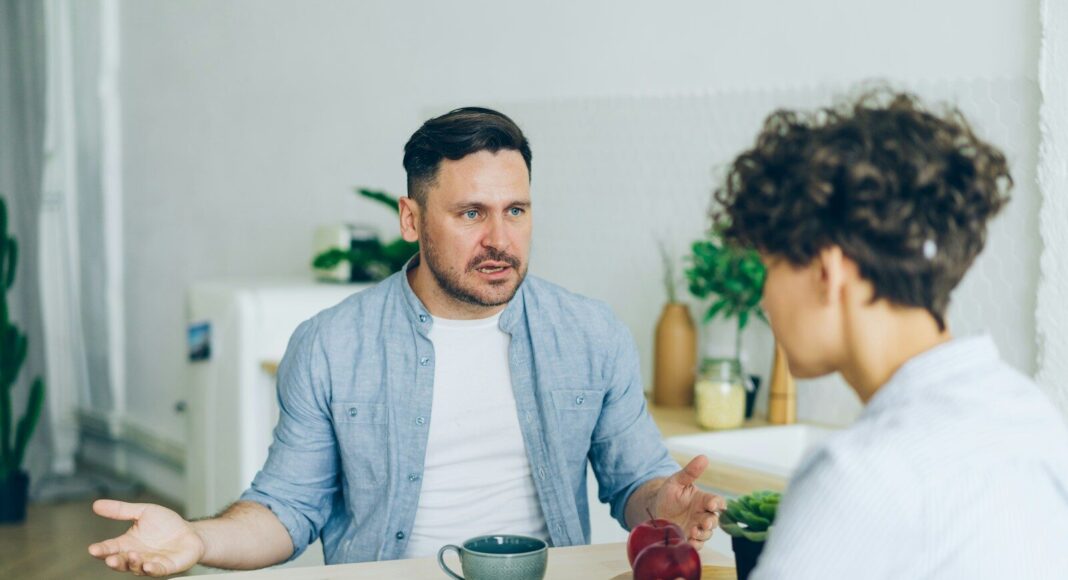 A man sitting at a table talking angrily to a woman.