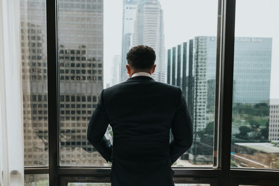 A businessman looking out the window of a skyscraper.