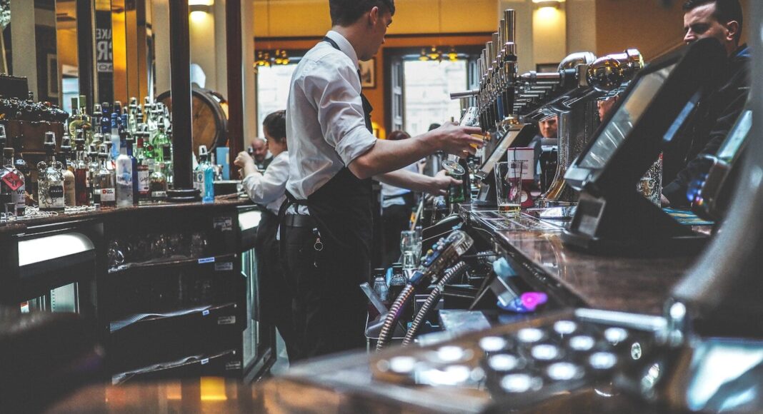 A bar worker pouring a drink.